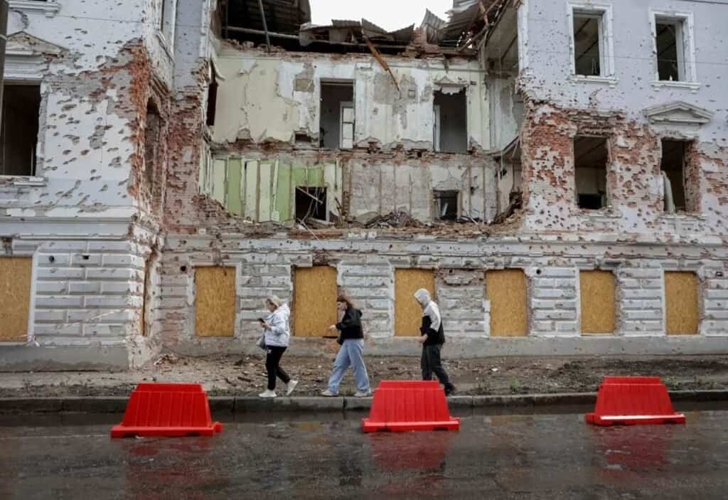 Banorët ecin përgjatë një rruge pranë një ndërtese të dëmtuar nga sulmet me raketa ruse, mes ofensivës së Rusisë ndaj Ukrainës, në qytetin Sumy, Ukrainë, më 13 qershor 2025.